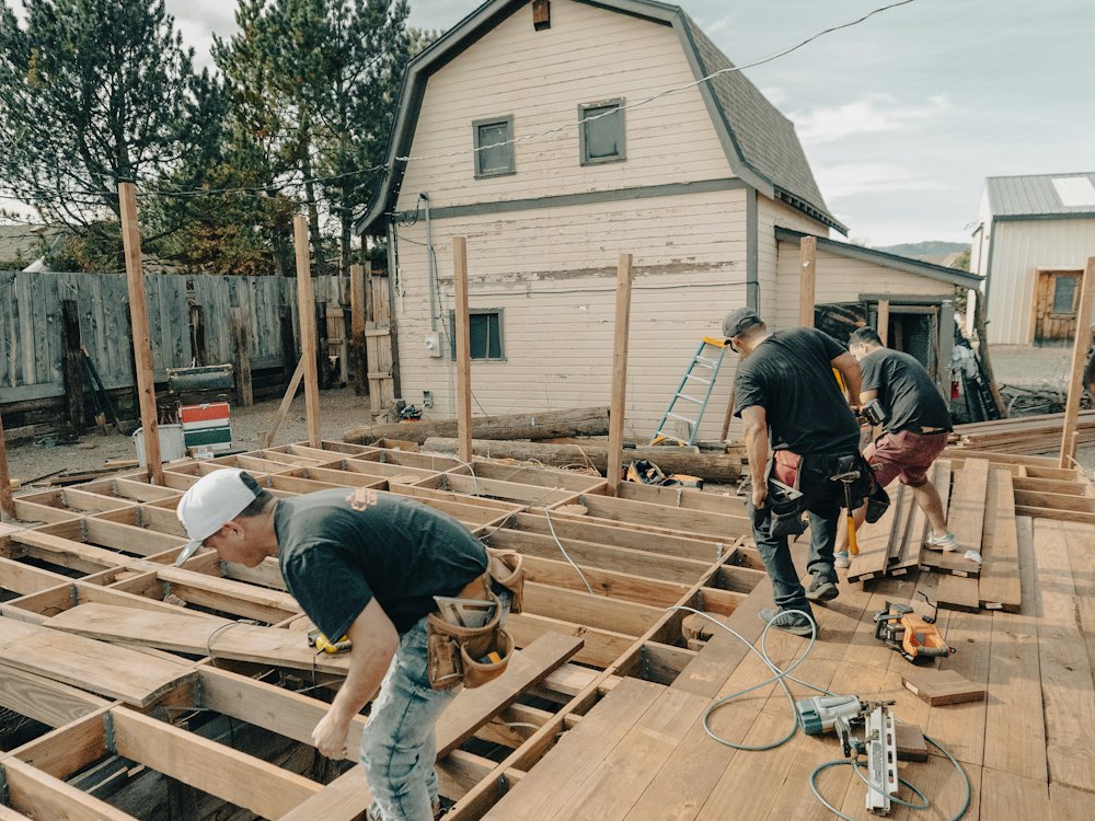 Workers laying deck boards over new framing