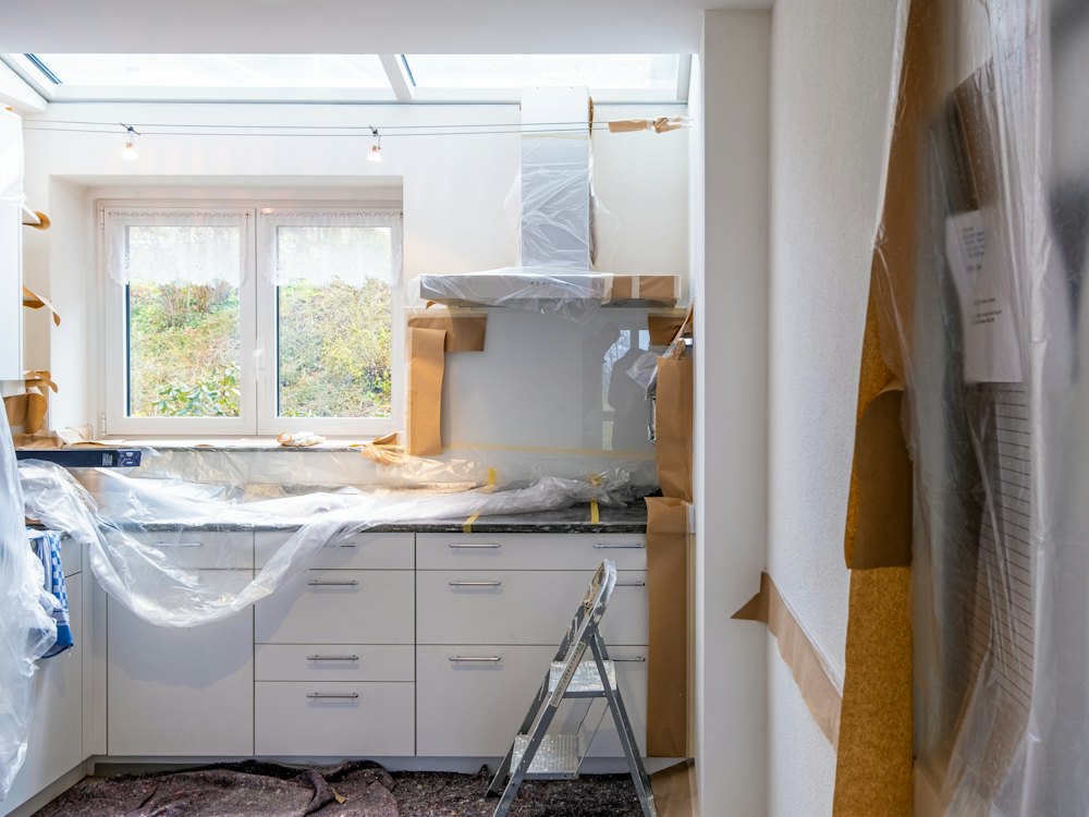 Kitchen under renovation with cabinets and floors covered in plastic
