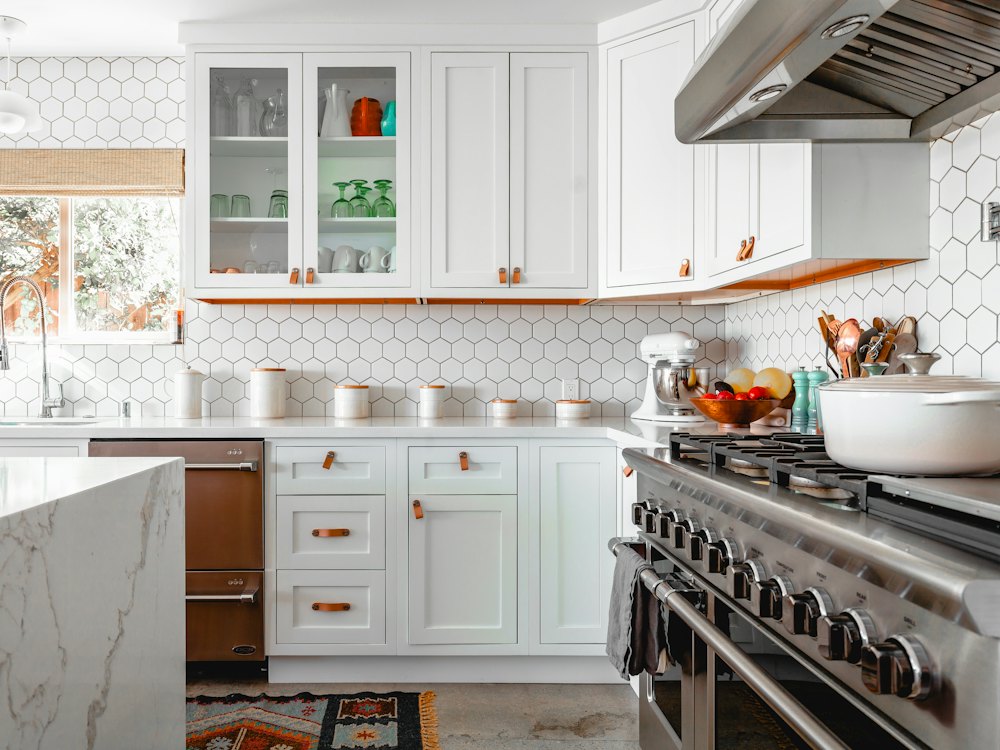 Bright kitchen with white cabinets, hexagon wall tile and a marble island